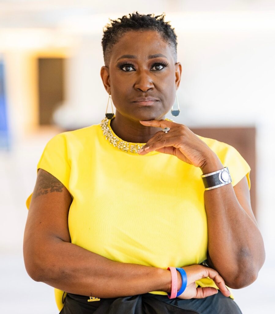 About Us 5 a woman with short hair wearing a yellow shirt and earrings