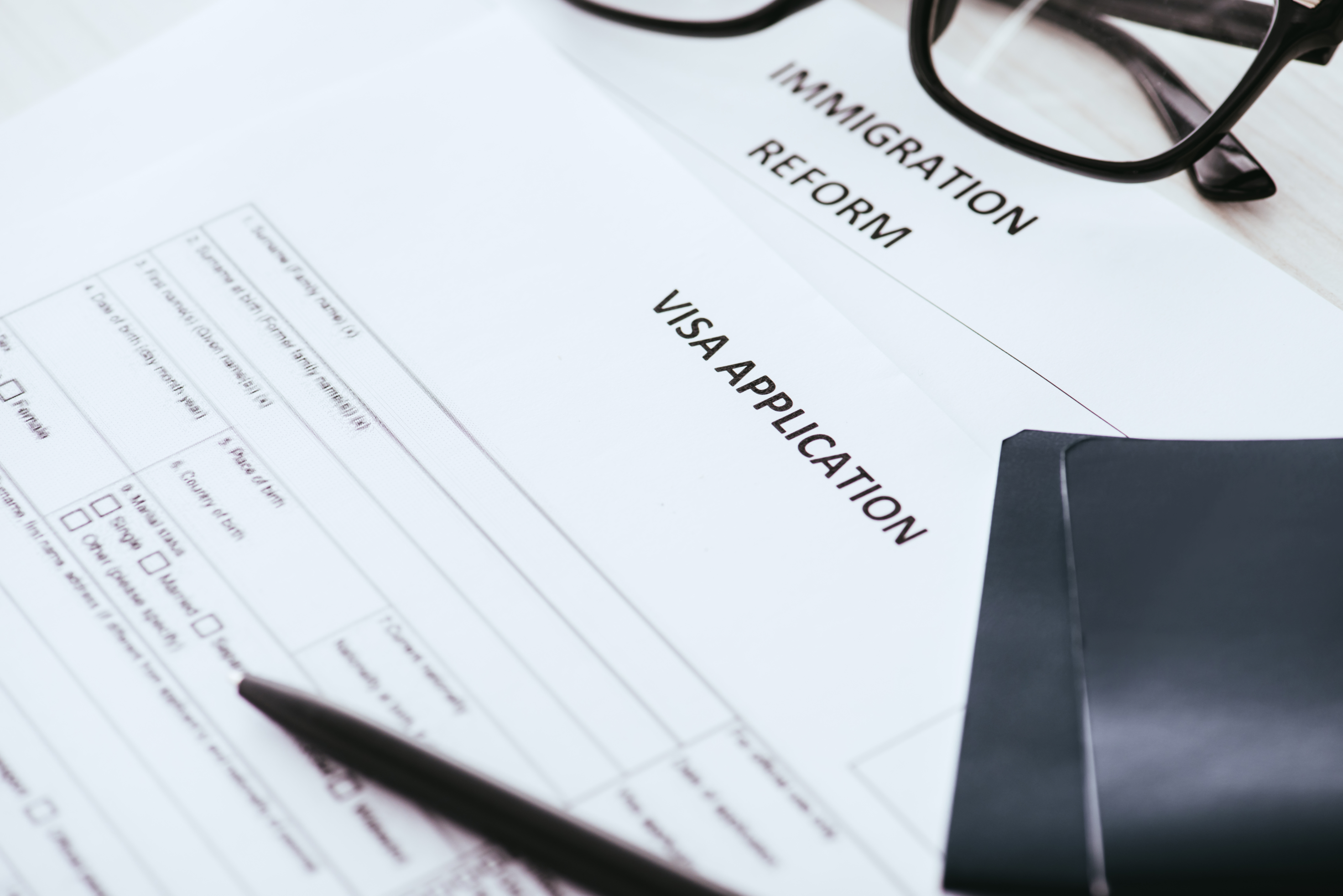 a visa application form with a pen and glasses